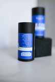 Two black cylindrical containers with blue labels on a light gray background