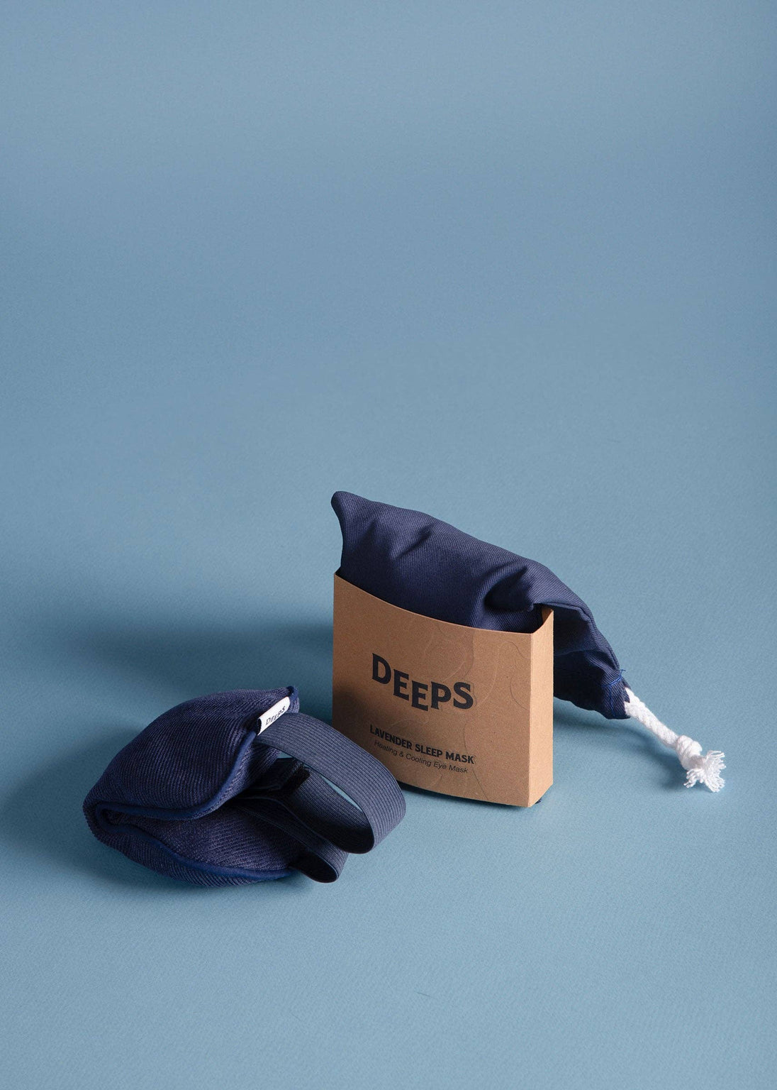 Navy blue swim cap and goggles with a cardboard box labeled 'DEEPS' on a light blue background
