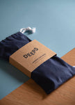 Navy blue sleep mask with 'DEEPS' branded box on a wooden surface and blue background