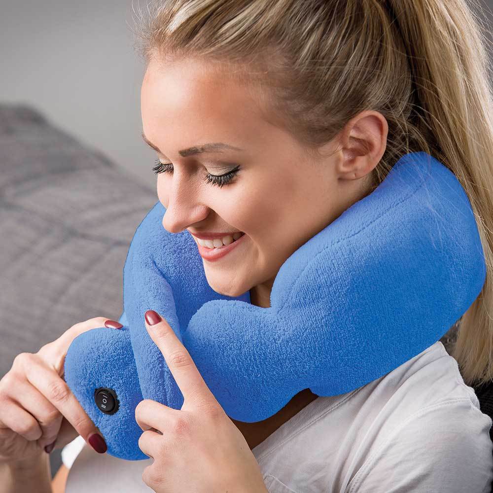 Woman using a blue massaging neck pillow in a bedroom setting